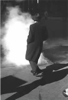 A person in a hat and coat walking away from a fire  AI-generated content may be incorrect.